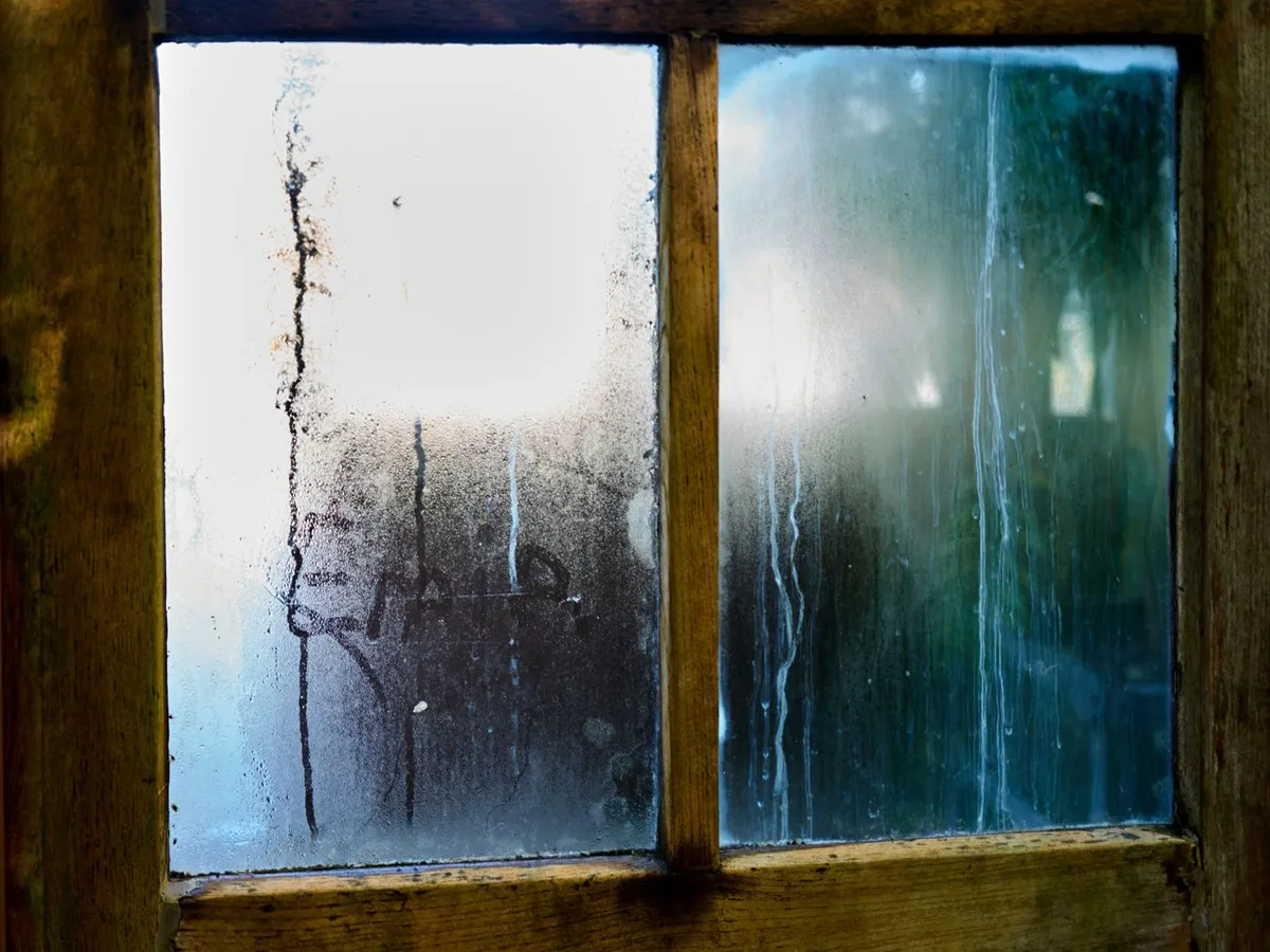 Altes Holzfenster mit Kondenswasser an der Scheibe