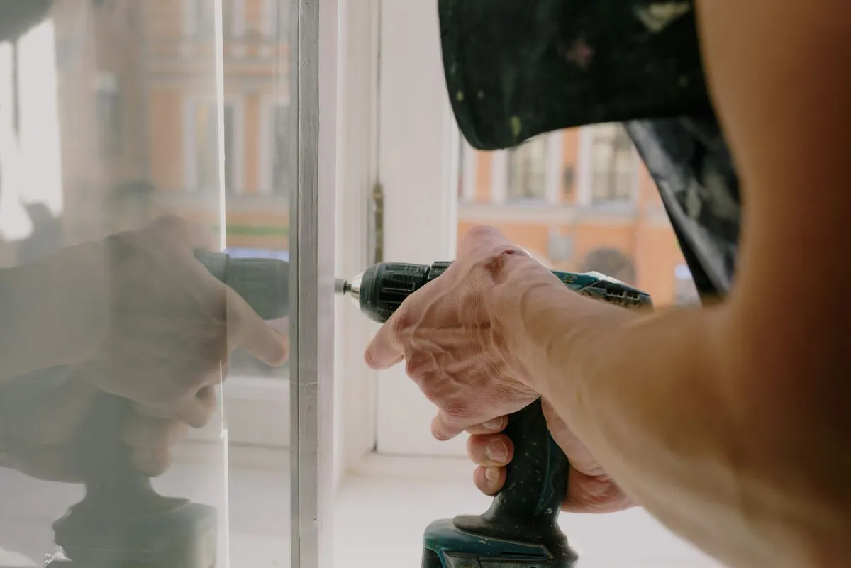 Handwerker stellt ein Fenster mit dem Akkuschrauber ein
